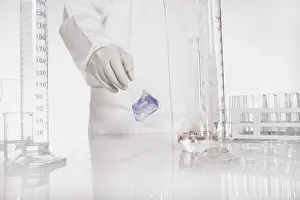 Chemist At Work Drucke: Chemist checking liquid in flask in a lab