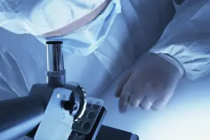 Chemist In Lab Coat Drucke: Chemist looking through a microscope