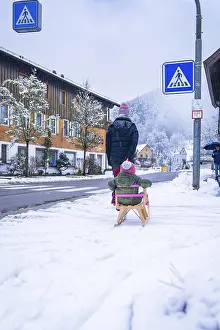 Black Forest Germany Winter Scene Drucke: Child on a sledge pulling along a road