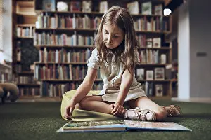 Primary School Education Drucke: Child solving riddle in book in school library