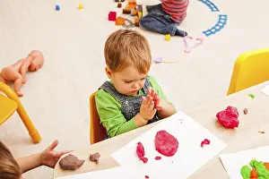 Child Development Through Art Drucke: Children is playing with modeling clay on the table