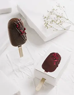Elegant Desserts Drucke: Two chocolate popsicles are displayed on a clean white surface