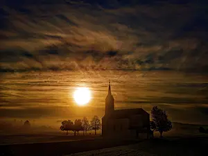 Bilder Datiert 23. Oktober 2024: Eine Kirche bei einem lebhaften Sonnenuntergang mit dramatischen Wolken.