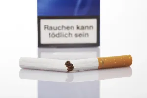 Smoking Ban Drucke: Cigarette broken in half, cigarette pack in background