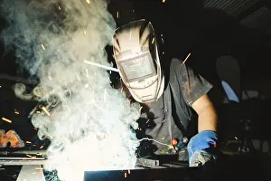 Industrial Workshop Drucke: Close-up of a deaf man using a welding torch in the workshop