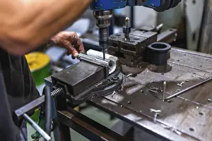 Industrial Building Interior Photo Drucke: Close-up of male worker working using threading machine in cnc metal workshop