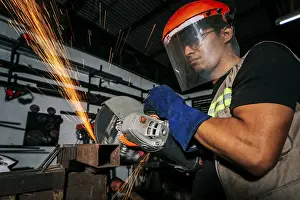 Handicraft Industry Tools Drucke: Close-up of a man using a grinder on an anvil