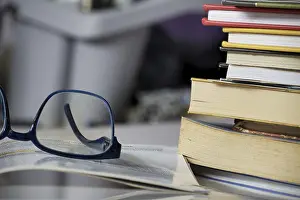 Bilder Datiert 30. September 2024: Nahaufnahme von Lesebrille auf offener Buchseite mit Bücherstapel in einem Studienumfeld für den Konzept des Lernens