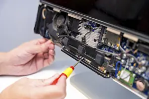 Quality Control Check Drucke: Close-up of an unrecognizable technician fixing computer circuit board of a computer in a workshop