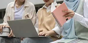 University Campus Scene Drucke: Close-up view of diverse students engaging in study with a laptop