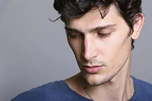 Close Up Portrait Drucke: Close up of young handsome man thinking while looking down