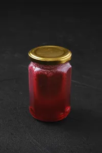 Still Life Image Drucke: Whole closed jar of cherry jam on black background