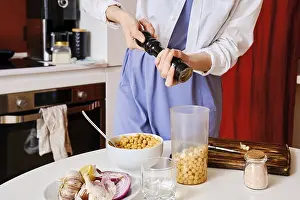Chickpea Dip Drucke: Closeup view of adding pepper into blender with chickpeas while making hummus