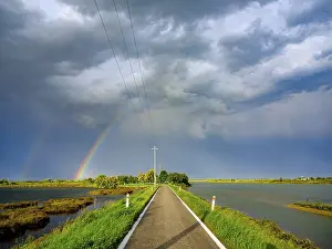 Venice Lagoon Photography Drucke: Clouds and rainbow over single lane road