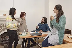 Communication In The Workplace Drucke: Four co-workers have coffee in the office
