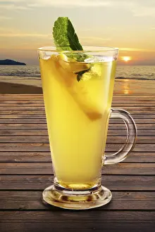 Alcoholic Mixed Drinks Drucke: Cold citrus tea on the table with sunset view on background