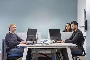Young Professionals At Work Drucke: Colleagues in a co-working office working while using computers