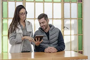 Colleagues Working Together Drucke: Two colleagues discuss while using a tablet in a bright office
