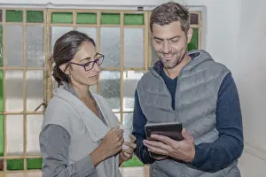Colleagues At Work Drucke: Two colleagues discuss their work looking at a tablet