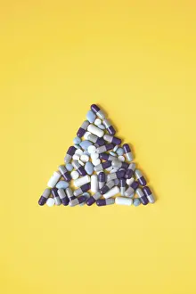 Medical Treatment Image Drucke: A collection of assorted pills is arranged in a triangular shape on a vivid yellow background