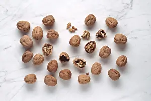 White Marble Surface Drucke: A collection of walnuts, some cracked open to reveal the kernels inside