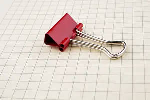 Stationery Items Drucke: Colored paper clip on a checked notebook page