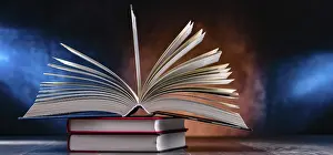 Eine Komposition mit einem offenen Buch, das auf einem Stapel anderer Bücher liegt.