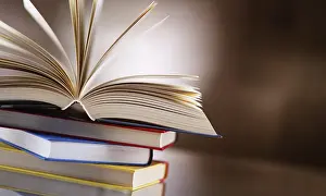 Open Book Drucke: A composition with an open hardcover book lying on a stack of other books