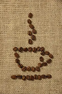 Coffee Concept Drucke: Conceptual artistic pattern of a cup of coffee made from coffee beans on a sacking background