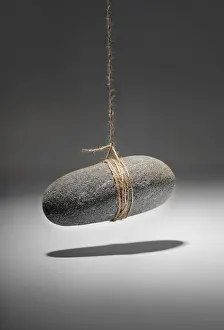 Studio Still Lifes Drucke: Conceptual image of a small rock hanging on a string