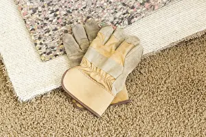 Construction Gloves Drucke: Construction gloves on pulled back carpet and underlay in room