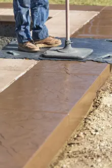 Texture Template On Wet Cement Drucke: Construction worker applying pressure to texture template on wet cement
