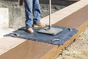 Construction Industry Workforce Drucke: Construction worker applying pressure to texture template on wet cement