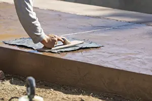 Texture Template On Wet Cement Drucke: Construction worker applying pressure to texture template on wet cement