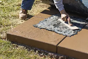 Construction Site Laborer Drucke: Construction worker applying pressure to texture template on wet cement