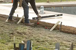 Construction Industry Jobs Drucke: Construction worker checking level on wet deck cement