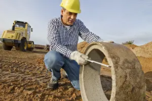 Yellow Hard Hat Drucke: A construction worker checks a sewage pipe