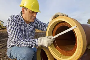 Yellow Hard Hat Drucke: A construction worker checks a sewage pipe