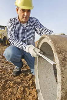 Yellow Hard Hat Drucke: A construction worker checks a sewage pipe