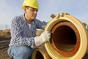 Yellow Hard Hat Drucke: A construction worker checks a sewage pipe