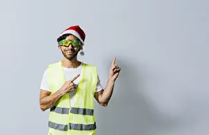 Christmas Hat Drucke: Construction worker with christmas hat pointing to an advertisement