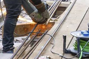 Metal Construction Equipment Drucke: A construction worker cuts metal bars with a flex machine