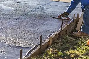 Swimming Pool Construction Process Drucke: Construction worker smoothing wet cement with trowel tools