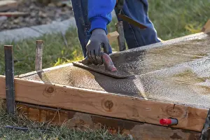 Building Construction Process Drucke: Construction worker smoothing wet cement with trowel tools