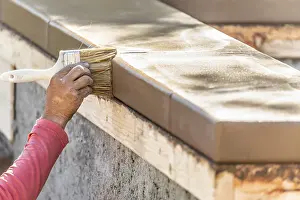 Construction Labor Drucke: Construction worker using brush on wet cement forming coping around new pool