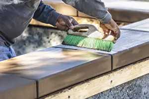 Cement Finishing Techniques Drucke: Construction worker using brush on wet cement forming coping around new pool