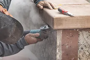 Male Construction Worker Drucke: Construction worker using grinder at construction site
