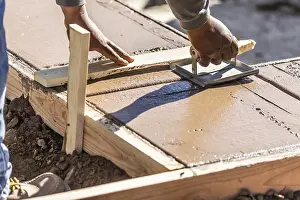 Construction Industry Workforce Drucke: Construction worker using hand groover on wet cement forming coping around new pool