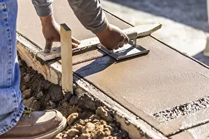 Building Construction Process Drucke: Construction worker using hand groover on wet cement forming coping around new pool