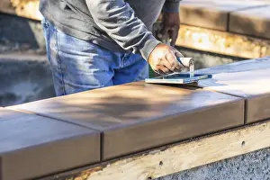 Real Estate Construction Industry Drucke: Construction worker using hand groover on wet cement forming coping around new pool